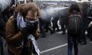 Un manifestante se tapa la boca para no inhalar el gas de la Policía durante la manifestación en París. /AFP