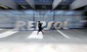 Un hombre pasa por delante del logo de Repsol en su sede de Madrid. REUTERS/Susana Vera