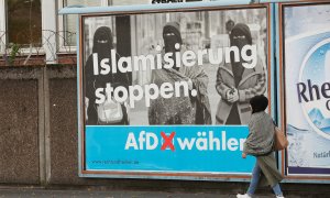 Una mujer con un pañuela en la cabeza camina por delante de uno de los carteles de campaña de Alternativa por Alemania (AfD) en Marxloh, un barrio de Duisburgo conocido por acoger a una mayoría turca entre sus residentes. 13 de septiembre del 2017. REUTER