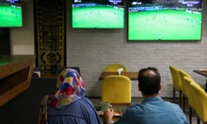 Una mujer ve un partido de fútbol junto a un amigo en una cafetería de Irán. REUTERS