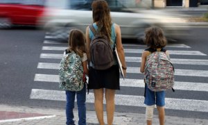 Una madre y sus hijas esperan a que los coches pasen para poder cruzar cuando van de camino a la escuela./ EFE-Archivo