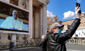 Un turista se saca una foto frente a una de las pantalla gigante instalada en la plaza del Vaticano para la misa del ángelus./ RICCARDO ANTIMIANI (EFE/EPA/ANSA)