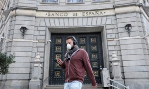 Un hombre con una mascarilla pasa junto a las oficinas del Banco de España, en Barcelona. REUTERS/Nacho Doce