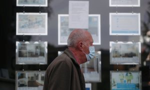 Un hombre con mascarilla pasa por delante de una inmobiliaria, en Madrid. REUTERS