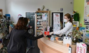 11/05/2020.- Una farmacéutica entrega una mascarilla, este lunes, en una farmacia de Alcalá de Henares. EFE/Fernando Villar