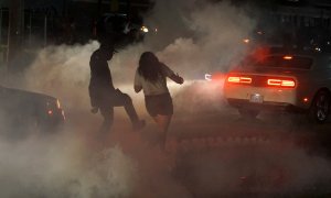 Un hombre patea un bote de gas lacrimógeno lejos de una mujer durante una protesta contra la muerte en la custodia policial de Minneapolis del hombre afroamericano George Floyd, en Ferguson, Missouri, Estados Unidos, 31 de mayo de 2020. REUTERS / Lawrence