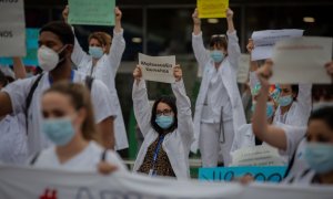 Decenas de miembros del personal sanitario protegidos con mascarilla sostienen carteles durante la concentración de sanitarios en el Día Internacional de la Enfermería a las puertas del Hospital Vall d'Hebron, en Barcelona. Europa Press / Archivo