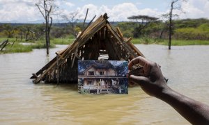 Un hombre sostiene una foto que muestra una estructura antes de que se sumergiera bajo el agua en aumento debido a las inundaciones en Kenia. REUTERS/Baz Ratner