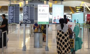 Pasajeros cerca de páneles informativos en la terminal T4 del aeropuerto Adolfo Suárez Madrid-Barajas. E.P./Jesús Hellín