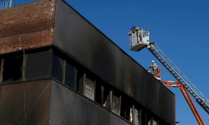 Bomberos de la Generalitat de Catalunya y trabajadores de la empresa de derribos inspeccionan este sábado en Badalona el inicio de la demolición de la nave donde murieron tres inmigrantes "sin techo" en un incendio. La nave, una antigua fábrica en desuso