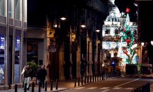 Un grupo de personas caminan por la céntrica calle Sangre de Valencia pocos minutos antes de la medianoche, momento en el que entra en vigor el toque de queda.