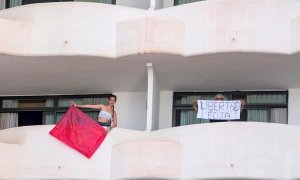 Dos jóvenes que permanecen en aislamiento en el hotel Palma Bellver de Palma portan dos pancartas pidiendo salir del hotel.