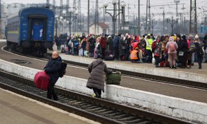 Refugiados ucranianos cruzan las vías del tren en la estación de Lviv.