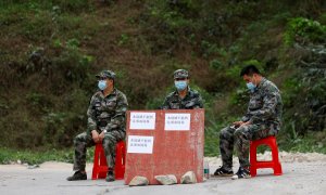 22/3/22-Los miembros de la milicia se sientan en el puesto de control en la carretera junto a la entrada de la aldea de Lu, cerca del lugar donde se estrelló un avión Boeing 737-800 de China Eastern Airlines que volaba de Kunming a Guangzhou, en Wuzhou, R