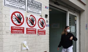 Una sanitaria con mascarilla en la puerta del Centro de Salud Ángela Uriarte, donde hay carteles de protesta que rezan 'Urgencias Cerradas, tu salud vendida', a 21 de octubre de 2022, en Madrid.