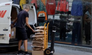 Un repartidor prepara paquetes de ropa en un carrito, en frente de un comercio en la localidad malagueña de Ronda. REUTERS/Jon Nazca