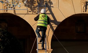 Un trabajador en lo alto de una escalera colocando las luces de Navidad en la localidad malagueña de Ronda. REUTERS/Jon Nazca