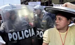 Una mujer de la organización popular Madres del Vaso de Leche se cubre la cabeza con la tapa de una olla el 27 de noviembre de 2003 en las puertas del Congreso en Lima.
