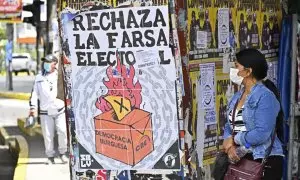 Una mujer camina junto a carteles que piden el voto negativo en el referéndum.