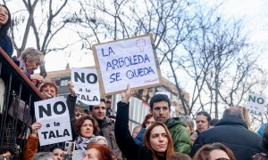 Una mujer porta una pancarta que reza 'La arboleda se queda' en la concentración para defender la arboleda de la zona de Madrid Río, que se verá afectada por las obras del Metro, a 18 de febrero de 2023, en Madrid (España).