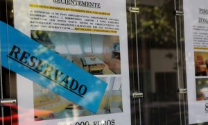 Anuncios de pisos y casas en venta y alquiler en el escaparate de una inmobiliaria.