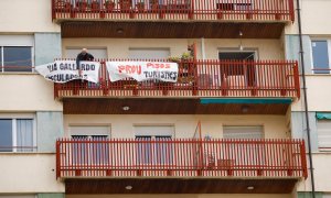 Un hombre coloca una pancarta en el balcón de su casa en protesta por los pisos turísticos del edificio en el que vive, en el barrio de Sants en Barcelona. La pancarta dice "No más pisos turísticos". REUTERS/Albert Gea