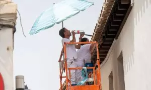 Unos trabajadores se cubren del sol con una sombrilla y beben agua en Granada, a 11 de julio de 2023.