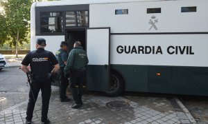 Varios agentes de la Guardia Civil y de Policía Nacional junto a un autobús de la Guardia Civil.