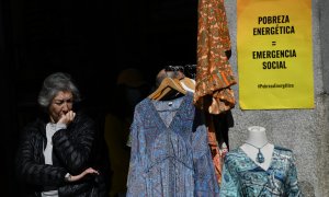 Una mujer, en un tienda de ropa con un cartel que reza 'Pobreza Energética = Emergencia Social', en una imagen de archivo.
