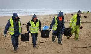 Operarios retiran los pellets o bolitas para fabricar plástico que han aparecido en las playas gallegas y de Asturias.