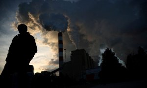 Un hombre camina mientras el humo y el vapor se elevan desde la central eléctrica de Belchatow, la central eléctrica alimentada por carbón y lignito más grande de Europa, en Rogowiec, Polonia.