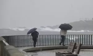 Dos personas caminan con un paraguas al lado de la playa del Orzán, a 22 de enero de 2024, en A Coruña.