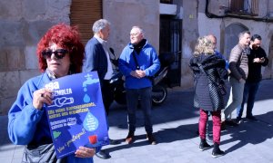 Una activista de la PDE morta un cartell de la 19a assemblea de l'entitat, amb representants del movimebnt social, econòmics i polítics parlant davant la delegació de la Generalitat, a Tortosa