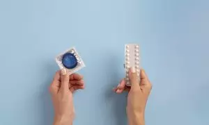 Unas manos sujetan unas pastillas y un condón