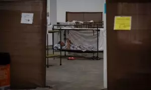 Un hombre descansa en su cama en el interior de las instalaciones del albergue de Fira Barcelona, habilitado por la pandemia para 225 personas sin techo, a 28 de marzo de 2020.