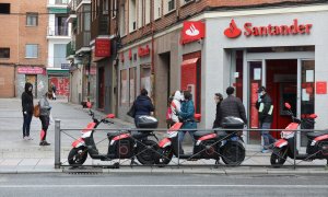 Varias personas esperan para entrar a una oficina del Banco Santander de Madrid, a 6 de abril de 2020.