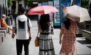 Varios turistas se cubren del sol con sombrillas mientras pasean este martes por Sevilla.