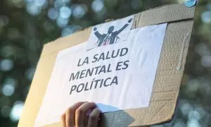 Manifestante sostiene un cartel durante una marcha por la salud mental como derecho universal con un recorrido de Atocha a Cibeles