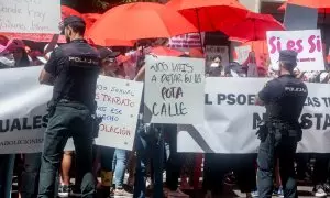 Varias personas con pancartas y paraguas rojos, frente a la policía, protestan durante una concentración, en la sede del PSOE en calle Ferraz, a 2 de junio de 2022, en Madrid (España).