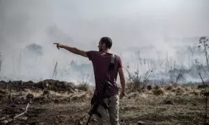 Un hombre armado se encuentra cerca de un incendio causado por ataques con misiles y drones en el Líbano. Imagen de archivo.