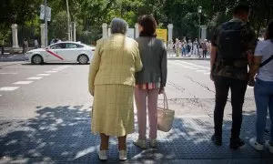 Una mujer mayor espera para cruzar una calle, con ayuda, por el centro de Madrid, a 4 de junio de 2023.