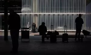Una persona sentada en un banco junto a su equipaje en el Aeropuerto de Barcelona-El Prat, a 19 de noviembre de 2021.