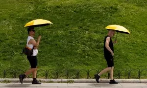 Dos personas se resguardan del sol bajo un paraguas, a 18 de julio de 2024, en Madrid (España).