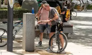 22/07/2024 Unos turistas junto a una fuente de agua pública en Sevilla. Imagen de archivo.