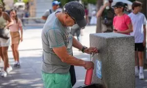 Un hombre llena una botella de agua en una fuente pública. A 05 de julio de 2024, en Sevilla (Andalucía, España).