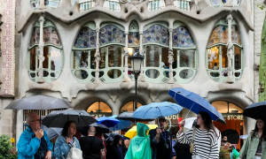 Persones es protegeixen de la pluja al passeig de Gràcia de Barcelona, en una imatge d'arxiu