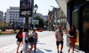 Varias personas pasan por debajo de un termómetro que marca 49 grados, en Bilbao, Euskadi.