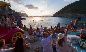 Varios grupos de turistas disfrutan del atardecer en Cala Benirrás, Ibiza.