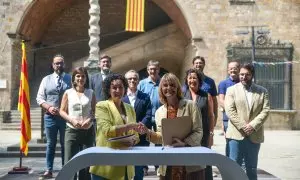 La secretària general d'ERC, Marta Rovira, i la viceprimera secretària del PSC, Lluïsa Moret, encaixen mans després de signar l'acord d'investidura acompanyades dels dos equips negociadors davant de la Biblioteca de Catalunya.