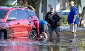 Varias personas intentan mover un automóvil averiado en una calle inundada tras la llegada del huracán Milton a tierra en Clearwater, Florida, EE.UU., el 10 de octubre de 2024.